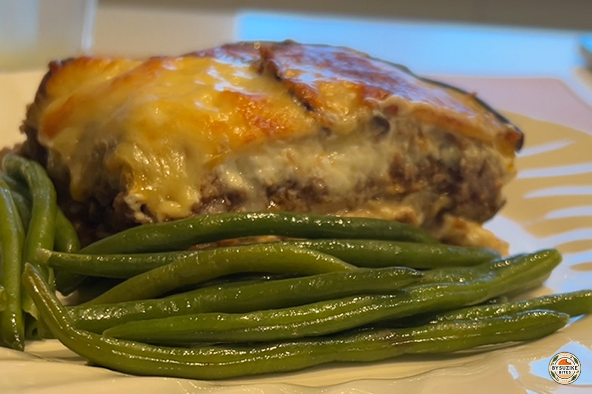 Cheesy eggplant lasagna served with green beans on a white plate — a low carb, keto-friendly meal idea