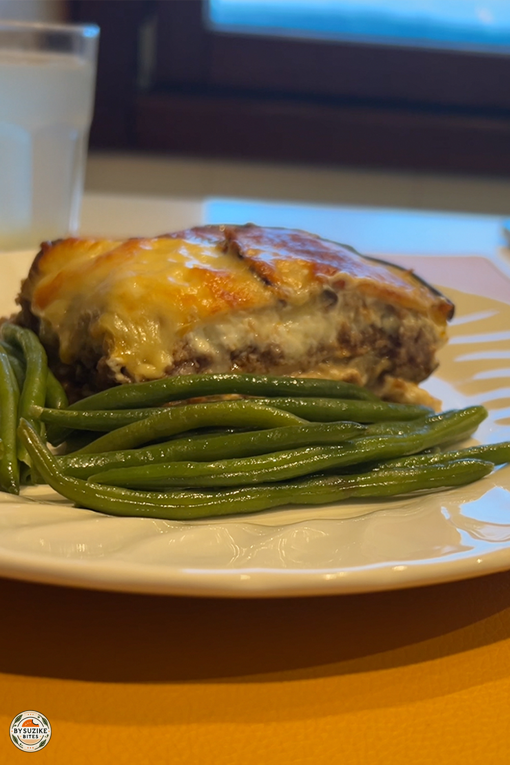 Cheesy eggplant lasagna served with green beans on a white plate — a low carb, keto-friendly meal idea