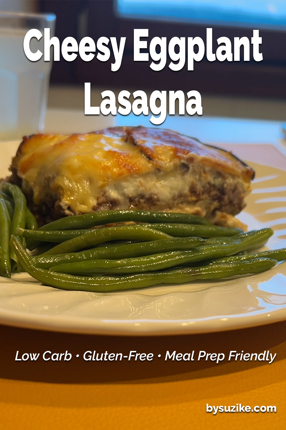 Cheesy eggplant lasagna served with green beans on a white plate — a low carb, keto-friendly meal idea