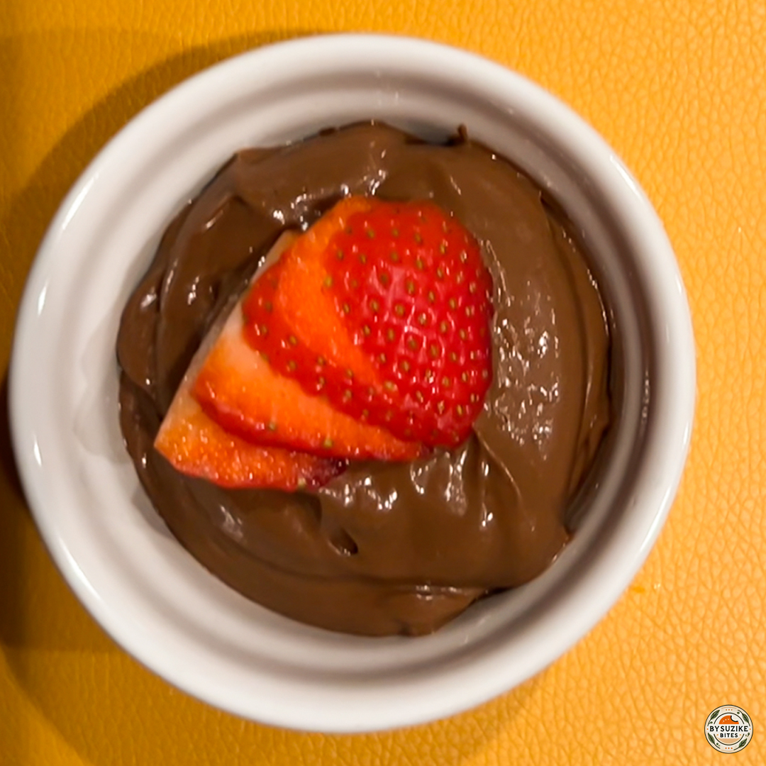 Avocado chocolate mousse in a white ramekin topped with sliced strawberries – healthy low carb dessert.