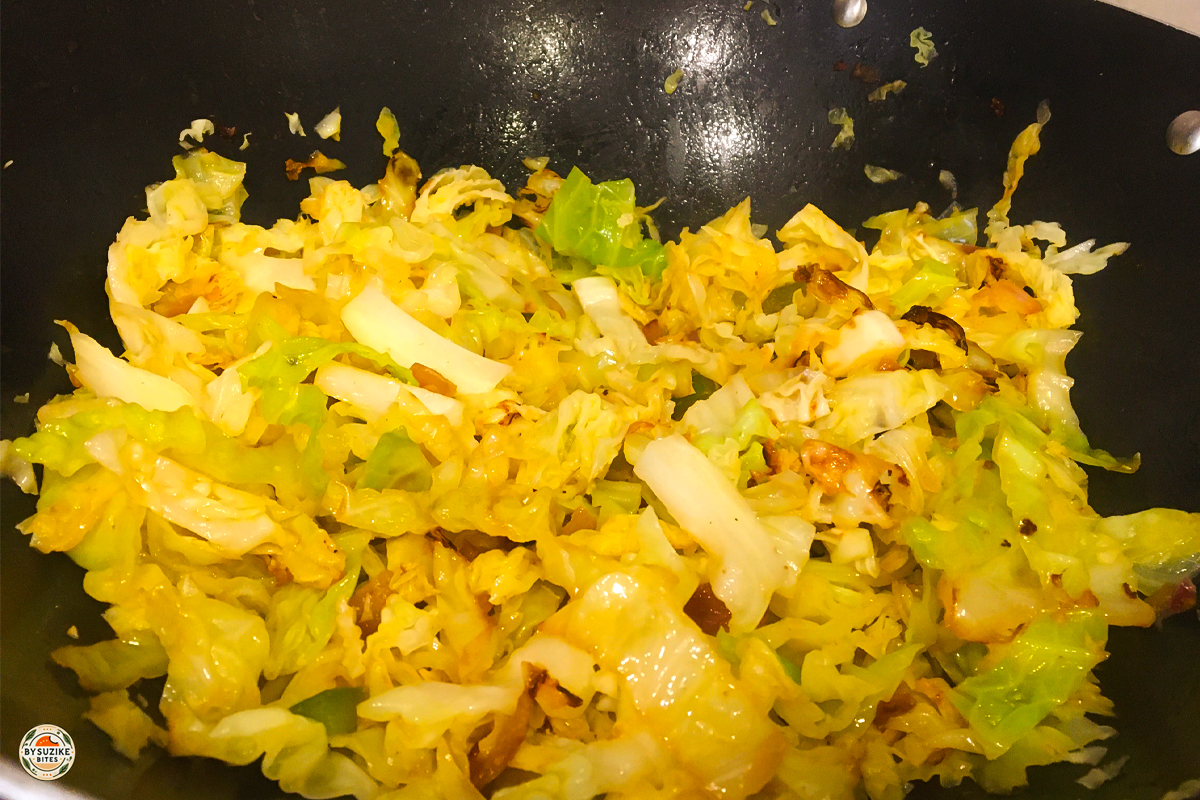 Cabbage and onion sautéing in butter in a wok