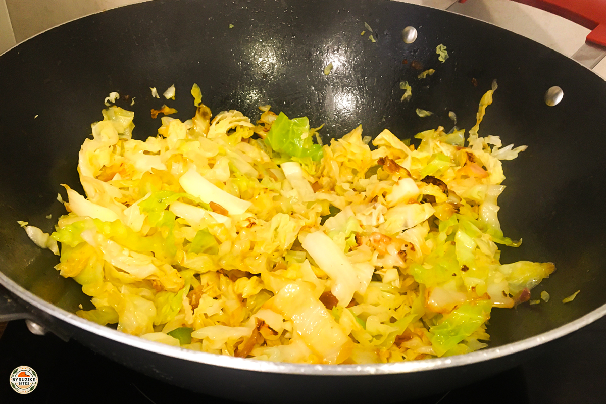 Cabbage and onion sautéing in butter in a wok