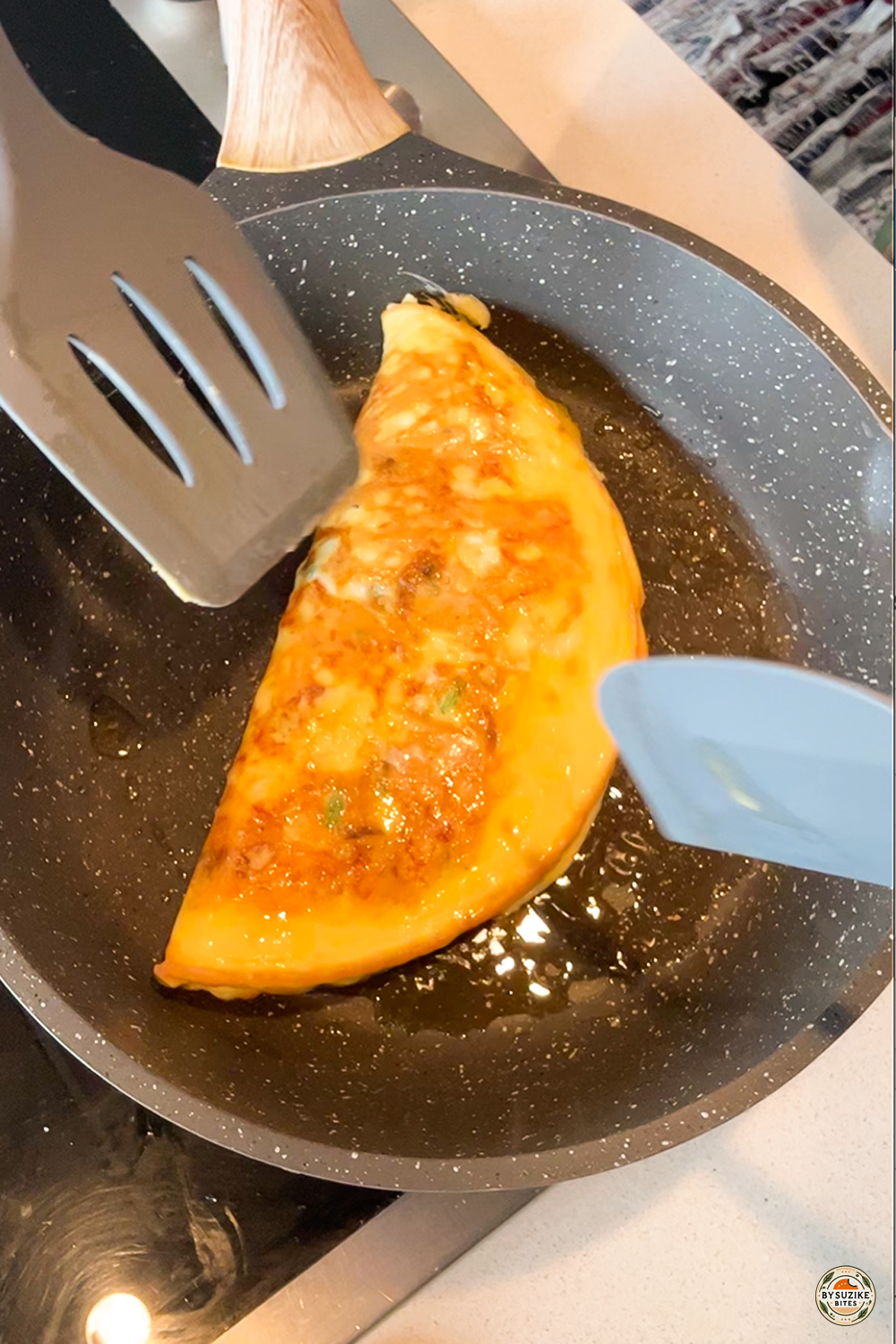 silicone cooking utensils flipping an omelet in a nonstick frying pan