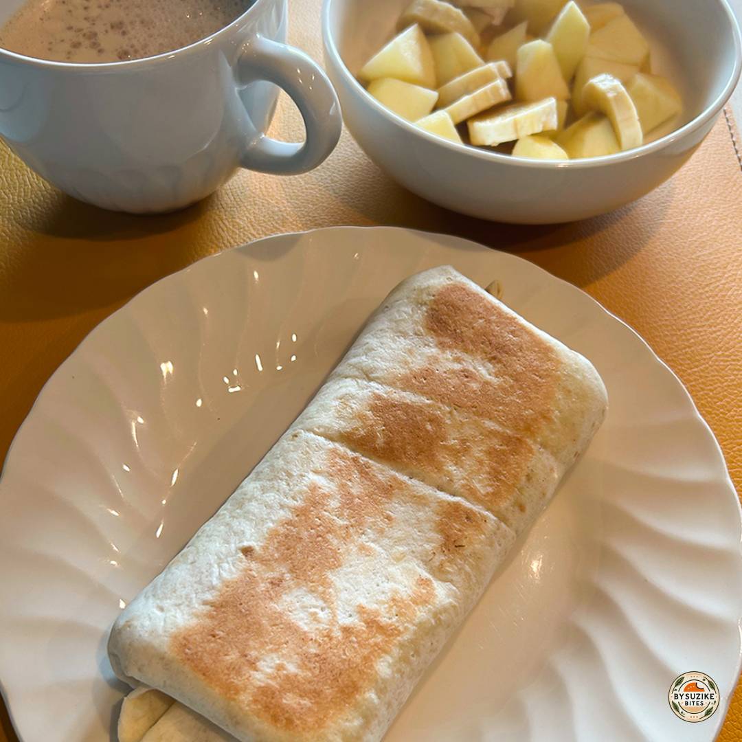 Egg breakfast wrap with chopped apple, banana, and a cup of coffee