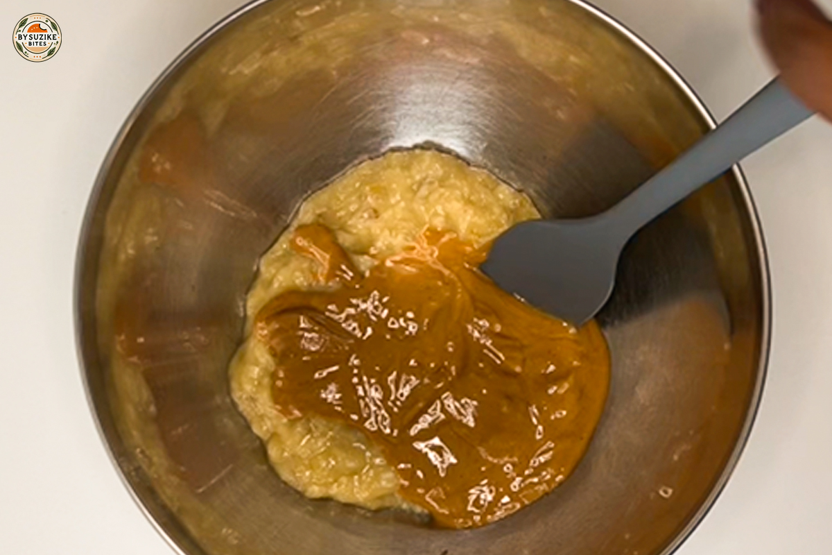 Adding creamy peanut butter to mashed bananas in mixing bowl
