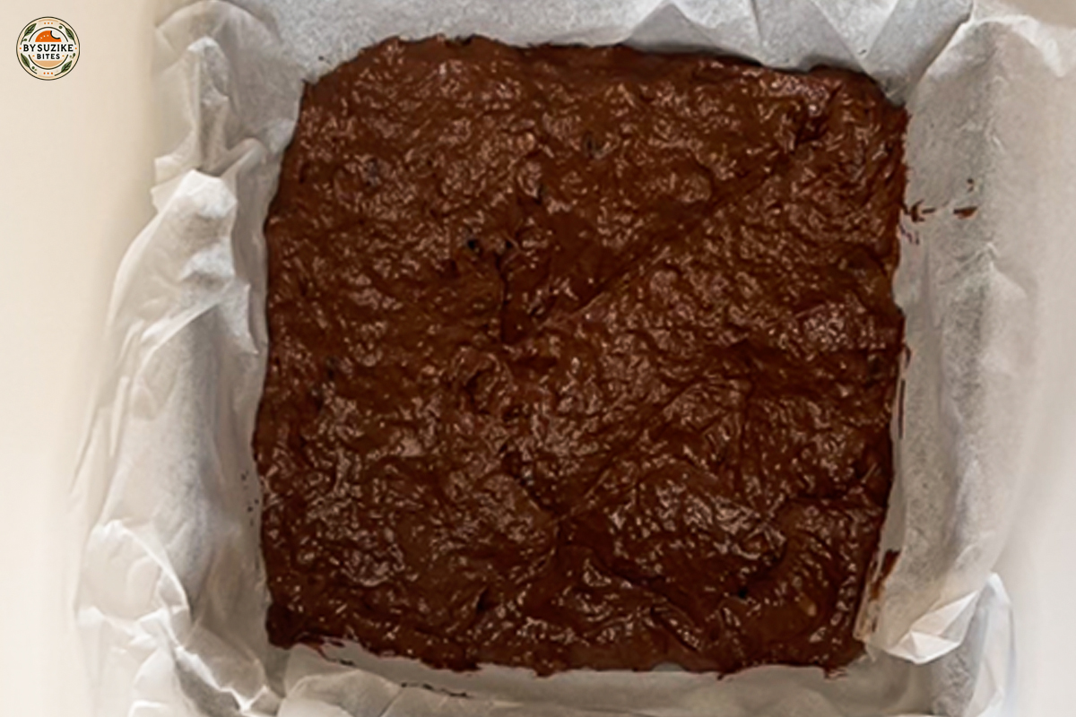 Unbaked vegan banana brownie batter in a lined baking pan