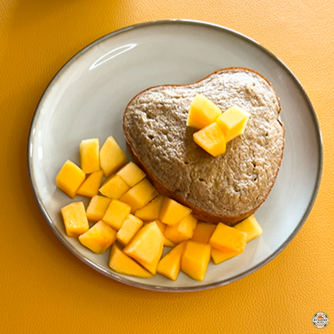 Freshly baked oat banana cake served with diced mango on a white plate